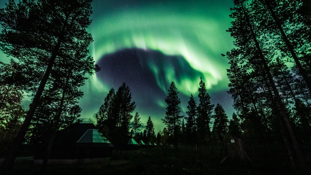 Amazing northern lights over aurora glass igloo cabins in ivalo village Lapland Finland.